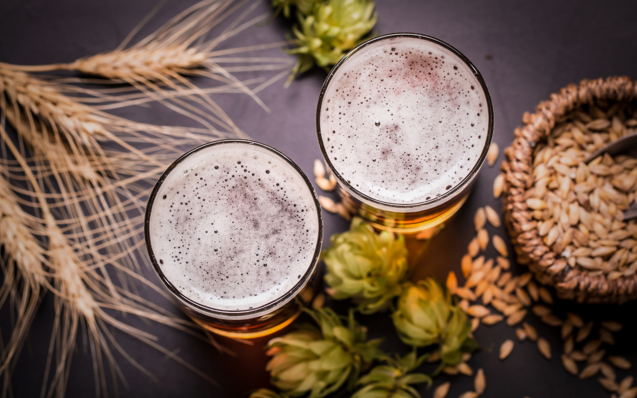 Two glasses of beer pictured from above, surrounded by beer ingredients