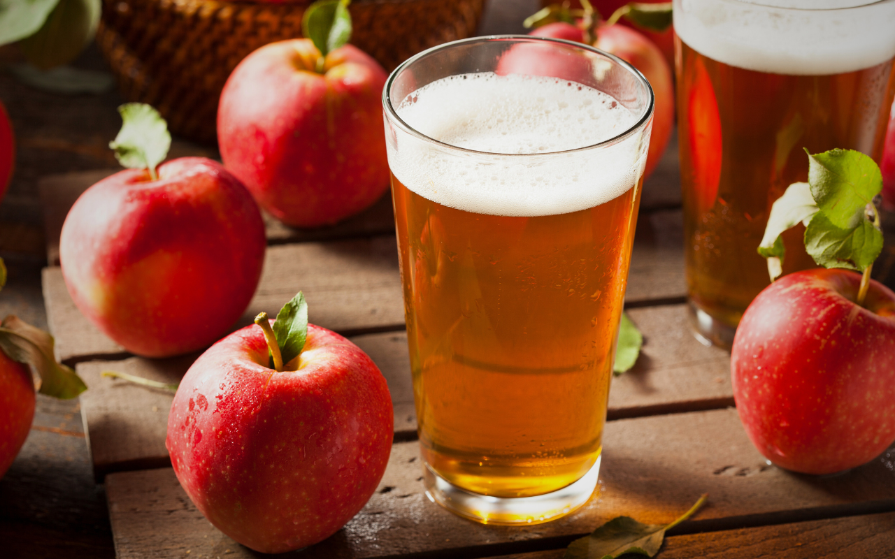 Glass of cider surrounded by red apples